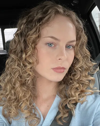 Try on this medium-length curly hairstyle visible on a person facing forward.