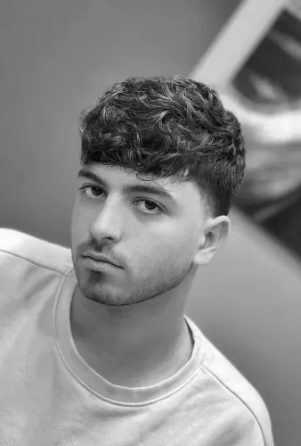 Try on a trendy hairstyle featuring short, tightly coiled curls on top with a neatly trimmed length around the sides.