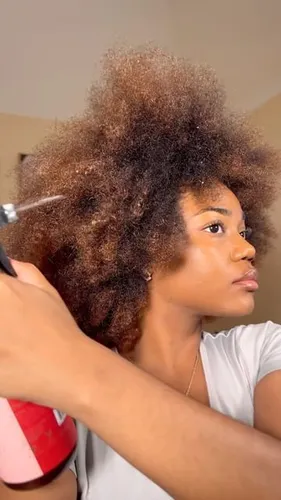Try on this voluminous afro with a mix of natural brown tones, being styled and enhanced using a spray
