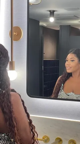 Try on this hairstyle featuring a woman with long, elaborately styled braids looking into a mirror.