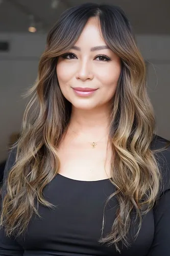 Try on this long wavy hairstyle with a face-framing fringe and beautiful highlights transitioning from dark roots to lighter tips.