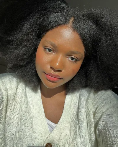Try on this voluminous afro hairstyle, featuring dark, dense, and bushy curls that frame the face beautifully