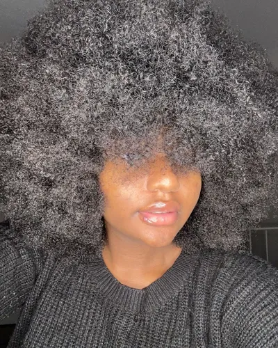 Try on this voluminous afro hairstyle that covers a significant portion of the face, providing a bold and textured look.
