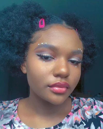 Try on this voluminous afro hairstyle, highlighted by a pink hair clip adding a small touch of color.