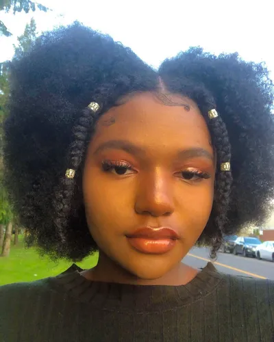 Try on this hairstyle featuring a voluminous afro with portioned front braids adorned with silver beads