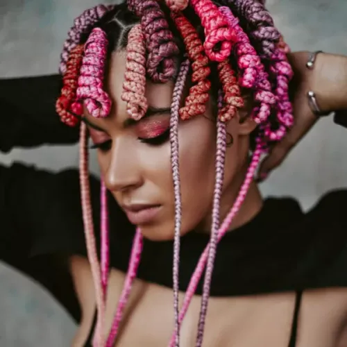 Try on this hairstyle featuring colorful braids, each detailed with pink and violet hues intertwined.