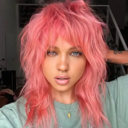 Try on this shaggy, vibrant pink hairstyle that flows around the face with a casual, tousled look.