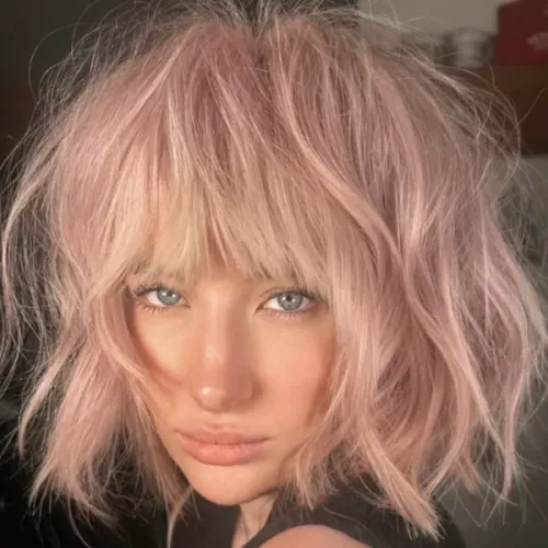 Try on this mid-length shaggy bob hairstyle with soft, textured bangs in a light pink hue.