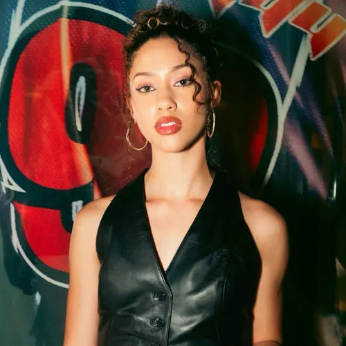 Try on this curly updo hairstyle featuring tightly coiled curls piled on top of the head with some loose tendrils framing the face.