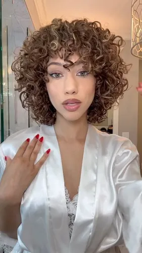 Try on a voluminous curly hairstyle with tightly coiled curls in a medium length cut, providing a full, bouncy look around the head.