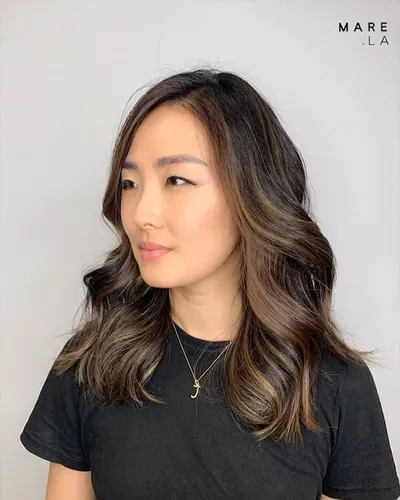 Try on this cascading long wavy hairstyle with subtle highlights adding depth and texture.