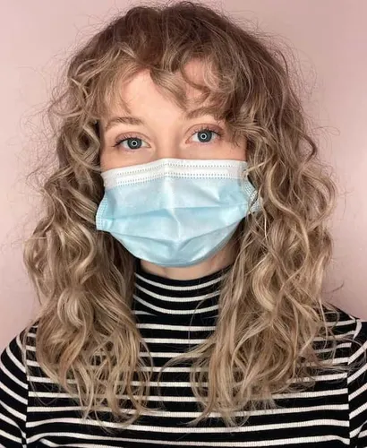 Try on a curly hairstyle on a lady with bangs, wearing a blue mask and a striped shirt