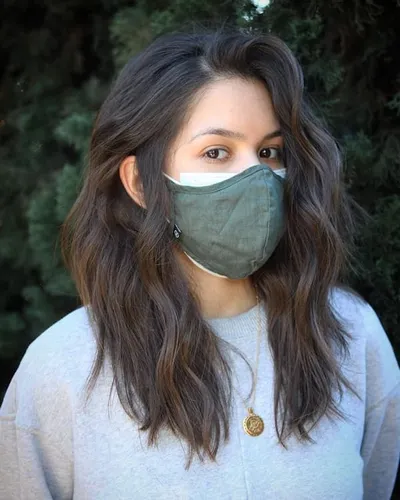 Try on this mid-length wavy hairstyle which is neatly layered. The hair color appears to be a natural brown, adding softness to the look.