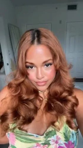 Try on this glamorous hairstyle featuring long, voluminous curls that cascade gracefully. The hair is tinted with a beautiful blend of blonde and light brown hues, enhancing the sophisticated allure.