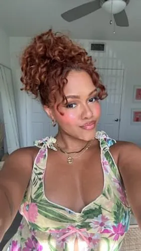 Try on this curly updo hairstyle, featuring tight, bouncy curls gathered at the top, perfect for a vibrant and playful look.