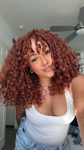 Try on this stunning medium-length, curly hairstyle showcased by a woman in the image. The curls are well-defined, adding a bouncy and voluminous look that frames the face beautifully.