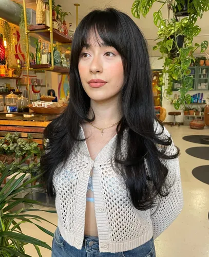 Try on a hairstyle with long straight black hair, featuring fringe bangs that frame the face.