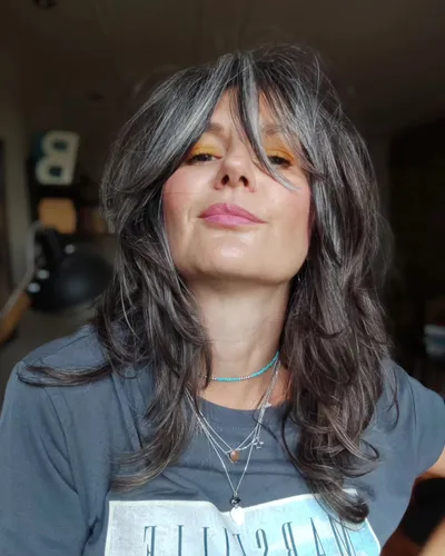 try on a hairstyle with long, voluminous graying hair featuring subtle waves. The hair color has distinct gray streaks blended into a darker base, creating a natural salt-and-pepper look.