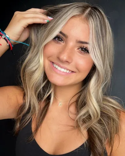 Try on this wavy, blonde hairstyle featuring soft curls and subtle highlights that create a natural, sun-kissed look.