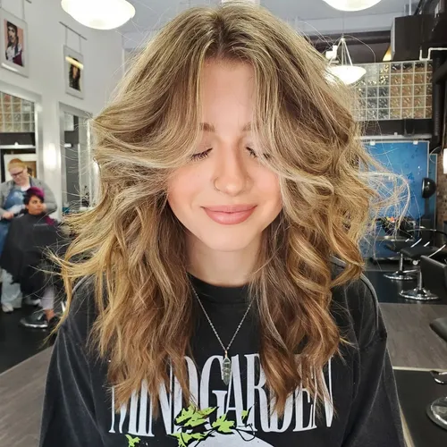 try on this layered, wavy blonde hairstyle that gently frames the face, creating a soft, youthful look