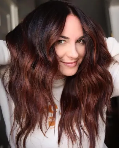 Try on this hairstyle featuring long, voluminous wavy hair with a dark to light ombre color transition from brunette at the roots to reddish-brown at the tips.
