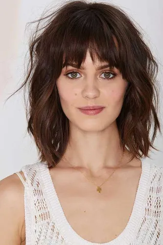 Try on a shaggy bob haircut with light bangs that gently frame the face.