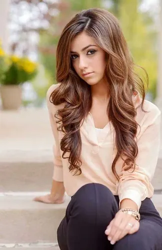 Try on this long wavy hairstyle featuring light and dark brown highlights, adding dimension and style.