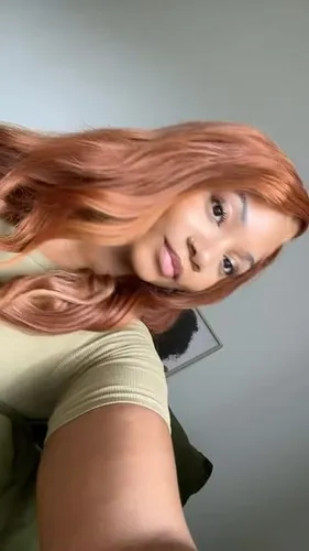 Try on this hairstyle with long, wavy, rose gold-colored strands framing the face beautifully. The hair has a soft, flowing texture, ideal for a fresh and trendy look.