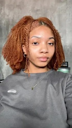 Try on this twist out hairstyle featured on the woman in the image. The style is voluminous and showcases well-defined, thick twists with a rich auburn color.