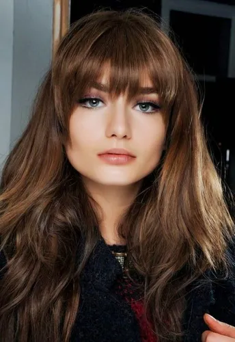 Try on this hairstyle featuring long, straight brown hair with full bangs. The hairstyle gives a soft, blended appearance, adding a youthful and modern vibe.
