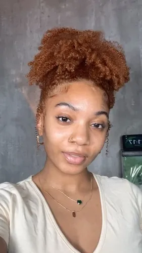 Try on this charming curly updo hairstyle, featuring a voluminous, curly bun atop the head. The rich auburn curls are tightly coiled and neatly gathered, highlighting the texture and fullness.