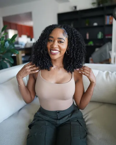 Try on the tight, springy, curly hairstyle that frames the face beautifully, radiating a joyful and vibrant vibe.