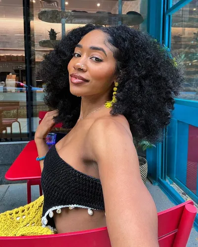 Try on a voluminous curly hairstyle, featuring rich, bouncy curls cascading around the face, highlighted with a subtle natural sheen.