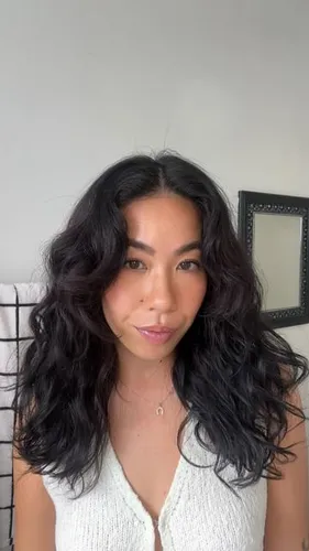 try on this wavy hairstyle, showcasing voluminous shoulder-length curls, which contribute a soft, feminine appearance