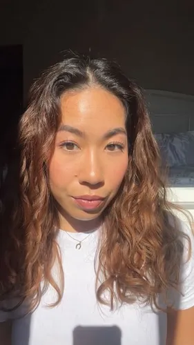 Try on this hairstyle featuring long, wavy hair with natural highlights, illuminated by sunlight.