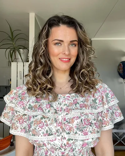 Try on this medium-length curly hairstyle, featuring soft curls that add volume and texture.