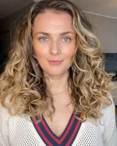 Try on this hairstyle featuring voluminous curly blonde hair with defined twists and varying shades from darker roots to lighter tips