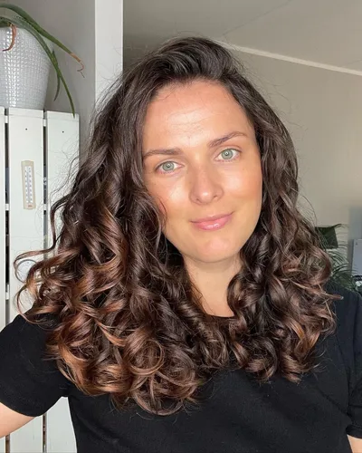 Try on this hairstyle featuring luxurious long curly brown hair, cascading in soft, voluminous curls that bring out a vibrant, lively look.