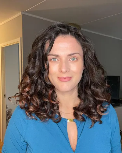 Try on this medium length dark hair with caramel ombre highlights styled in soft, voluminous waves. The hairstyle demonstrates a beautiful gradient effect from the darker roots to lighter ends.