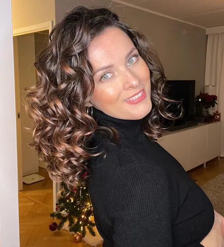 Try on this luxuriously voluminous curly brown hairstyle, styled with well-defined curls cascading around the face, adding a soft and glamorous touch to the look.