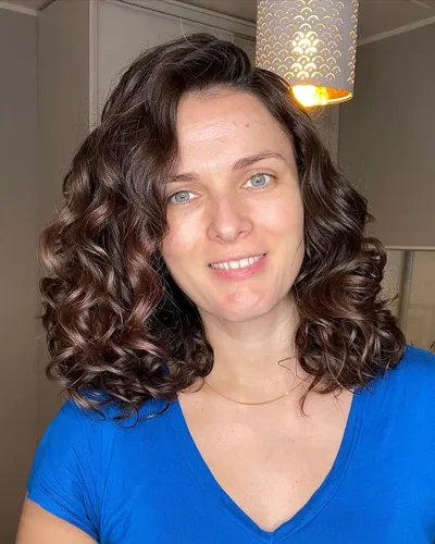 Try on this voluminous brown curly hairstyle with elegantly defined curls and subtle highlights.