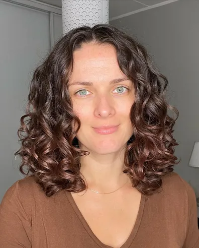 Try this shoulder-length, curly hairstyle featuring soft curls and a natural brown color.