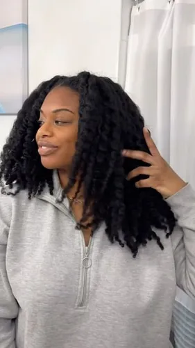 Try on a twist hairstyle featuring dense, black twists covering the head and falling past the shoulders. A hand is gently touching the hair.