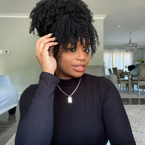 Try on a voluminous curly hairstyle. The hair is styled in tight, springy curls that add significant volume and texture, giving a full-bodied appearance.