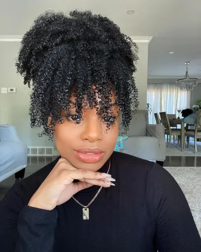 Try on a voluminous curly hairstyle featuring tightly coiled curls that add significant volume and texture.