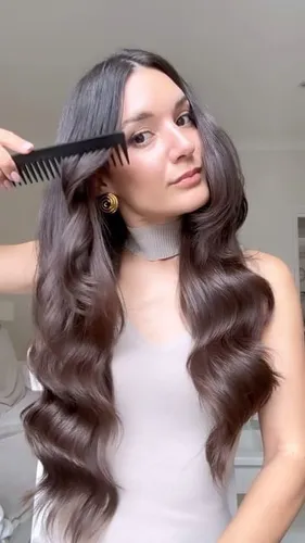 Try on this long, wavy hairstyle shown as a person combs through beautifully curled dark hair.