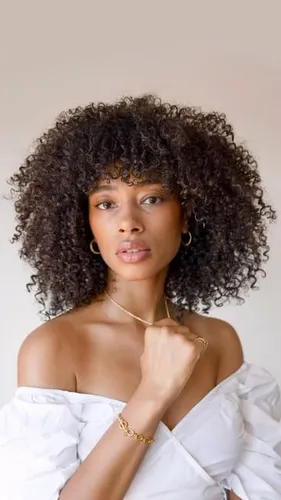 Try on this voluminous curly hairstyle for a vibrant look. The hair is densely coiled with a natural bounce, enhancing the overall style.