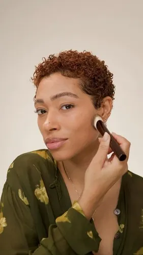 Try on a short curly hairstyle as shown by the person applying makeup.