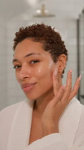 Try on this short curly hairstyle, as showcased by the woman posing with a serene expression in a bathroom