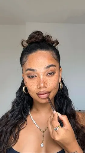 Try on a casual yet chic hairstyle featuring a top bun with curly loose strands framing the face, adding a playful and stylish touch.